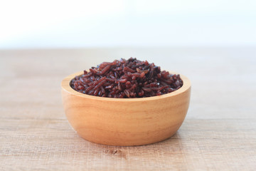 Rice berry in wooden bowl on table.