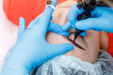 Permanent makeup, tattooing of eyebrows. Cosmetologist applying make up
