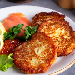 Tasty potato pancakes with caviar and salmon on a plate. Closeup.