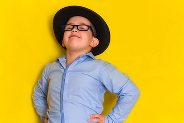 portrait of proud beautiful little boy in hat and shirt isolated on yellow background