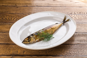 Hot smoked herring fish on plate isolated on wooden background