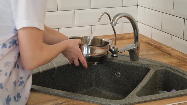 pouring ap water into a steel pan on kitchen stone sink. cooking preparation