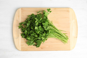 Board with fresh green parsley on wooden background, top view