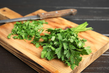 Wooden board with fresh green parsley and knife on table, closeup