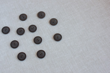 black buttons for sewing scattered on a light linen tablecloth