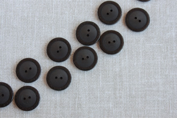black buttons for sewing diagonally on a light linen tablecloth