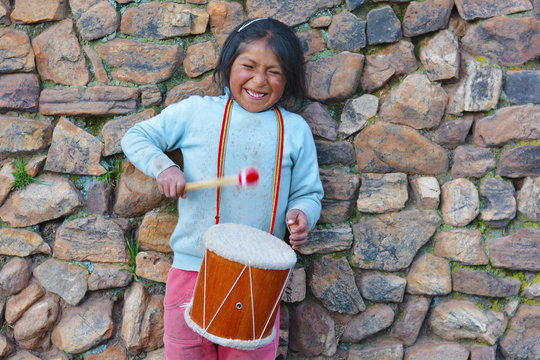 Little native american girl playing traditional sikuri drum.
