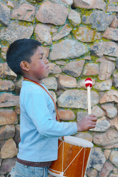 Profile of serious native american boy playing traditional sikuri drum.
