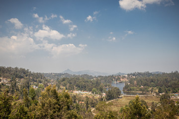 Obraz premium Górny widok na jezioro z zielonym lasem i niebieskim niebem