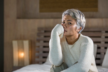 dramatic lifestyle home portrait of attractive sad and depressed middle aged woman with grey hair...