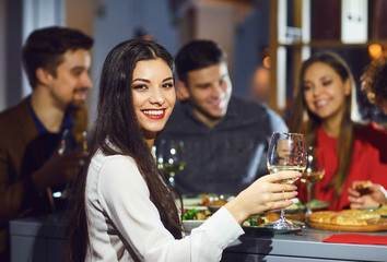 Woman with a glass against the background of friends in a restaurant.