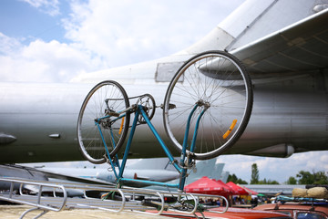 The bicycle is fixed upside down on the roof rack of the car at the airport.