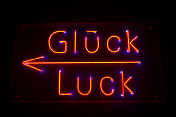 Fototapeta na wymiar German Word Glück - Word Luck Red Neon Letters on Black Background