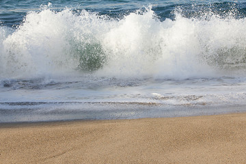  exploding wave splash with foaming backsplash on sandy beach