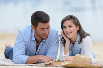 couple lay son the grass and show a heart sign
