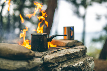 Making coffee in cezve on the fireplace when camping or hiking. coffee on campfire