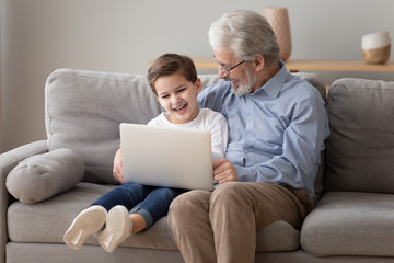 Happy grandfather and grandson play laptop together
