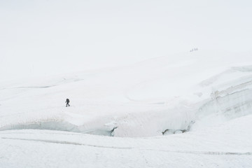Fototapeta na wymiar Tourist walking on the glacier near the crack. View to the Mensu glacier. Belukha Mountain area. Altai, Russia.