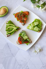Vegetarian sandwiches with avocado, tomatoes and cucumbers on a light background