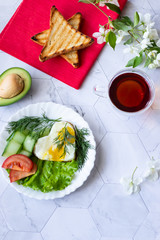 Fried eggs with lettuce, cucumber and tomato slices on a light background