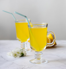 Lemonade refreshing drink in a glass beaker on a light background