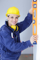 smiling woman builder doing measures with level tool