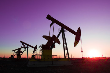 Oil pumps are running in the sunset at the oil field