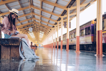 woman traveler holding camera taking photo at train station. travel trip journey
