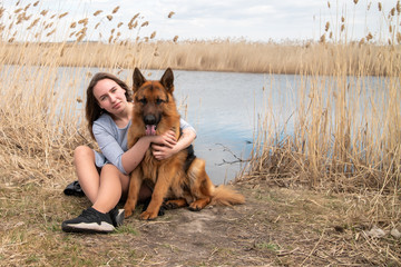 Teenage girl in white shirt with her german shepherd dog walking in the park
