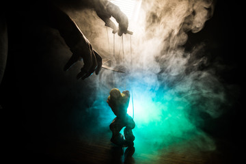 Fototapeta premium Concept of manipulation. Hand holds strings for manipulation. The hand controls the puppet strings on a dark foggy background.