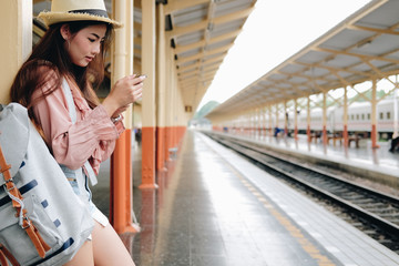 woman traveler with backpack use mobile smart phone at train station. trip journey travel concept