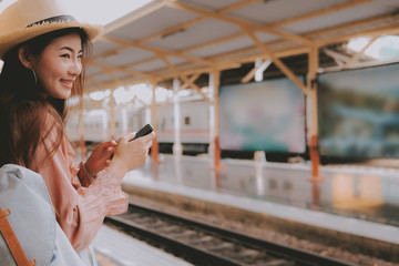 woman traveler with backpack use mobile smart phone at train station. trip journey travel concept