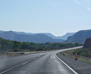 Wide shot of paved winding road to Zion National Park, with silhouettes of the mountains in varying hues of blue.