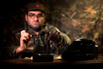 The evil dictator sitting on table. Angry communist general sitting at headquarter or Cuban...