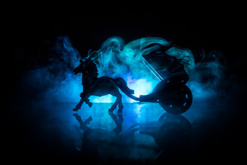 Artwork decoration. Silhouette of old coach with horse on dark toned foggy background.