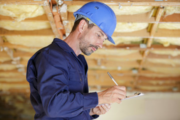 male engineer writing on clipboard at construction site
