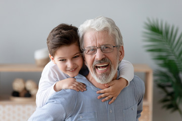 Portrait of happy grandson have fun piggyback smiling grandfather