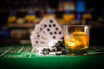 gambling, fortune, game and entertainment concept - close up of casino chips and whisky glass on table