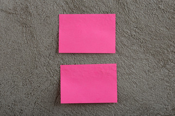 Two pinks stickers note on grey concrete background. Copy space