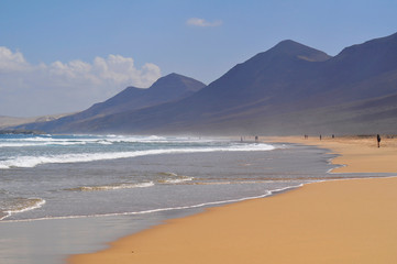Fototapeta na wymiar Beautiful sandy ocean beach on a background of mountains. Fuerteventura Canary Islands, Spain