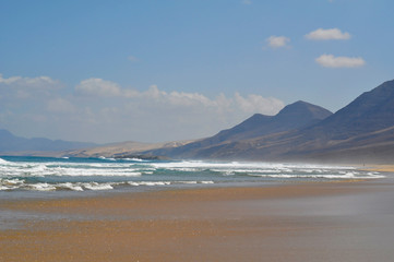Empty sandy ocean beach on a background of mountains. Fuerteventura Canary Islands, Spain