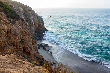 sandstone path overlooking cliff side, pacfic ocean expanse, and waves on the shore