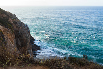 sandstone path overlooking cliff side, pacfic ocean expanse, and waves on the shore