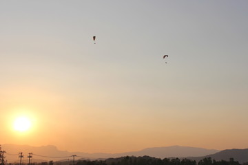 The sun is below the horizon. Travelers are driving Paramotor.