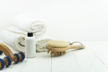 Beautiful spa still life treatment composition with copy space for text. Twisted towel with massage brushes and oil bottle on white background. Concept of spa, massage, relax, beauty spa treatment.