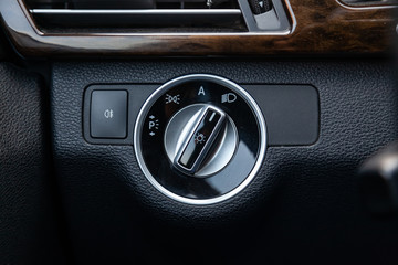 The dashboard of the car's interior is black with a dipped headlamp switch and side lights with a light sensor and automatic dimming and fog light button. Auto service industry.