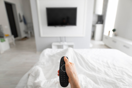 1st person view of man using TV remote in a bed