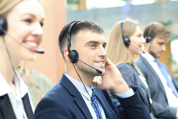 Portrait of call center worker accompanied by his team. Smiling customer support operator at work.