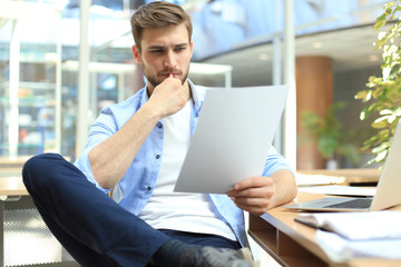 Portrait of young man sitting at his desk in the office.