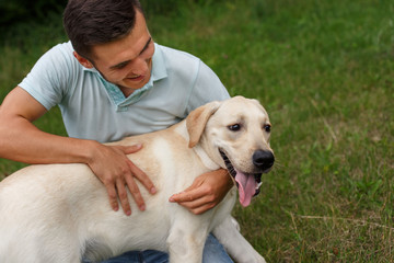 Friendship of man and dog. Happy young man is playing with his friend - dog Labrador